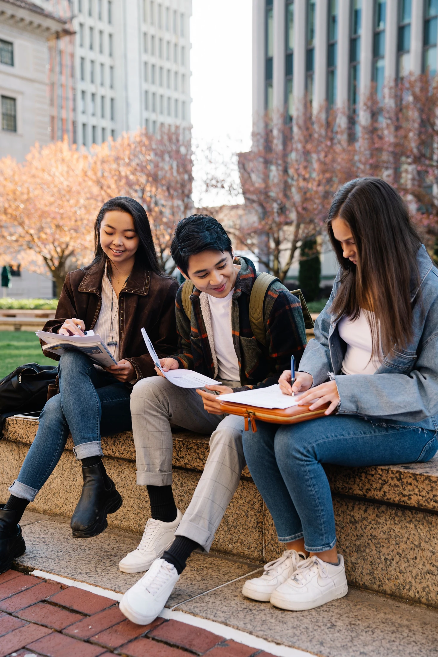 Three friends compare notes while sitting together outside.